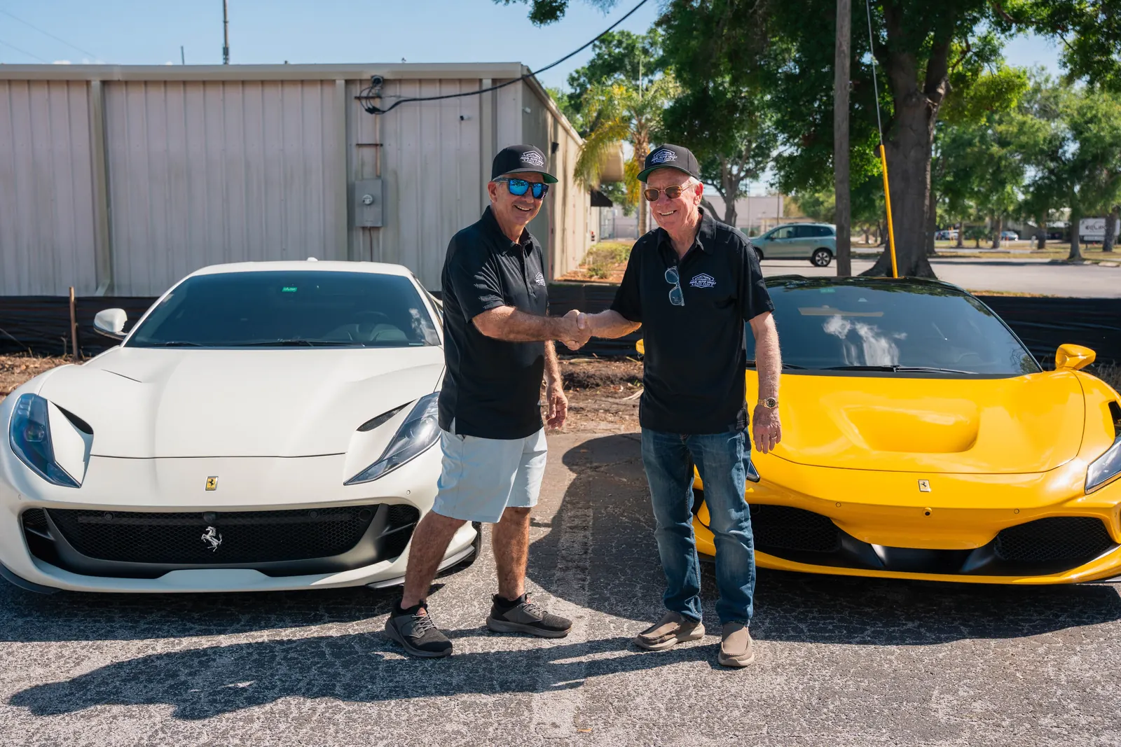 Two Anvil Auto Vault community members shaking hands between Ferrari vehicles